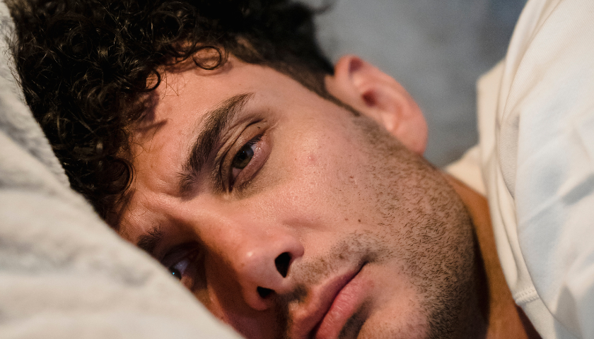 Chronic Sleep Disturbance Image of a Man Sleeping & Looking Annoyed